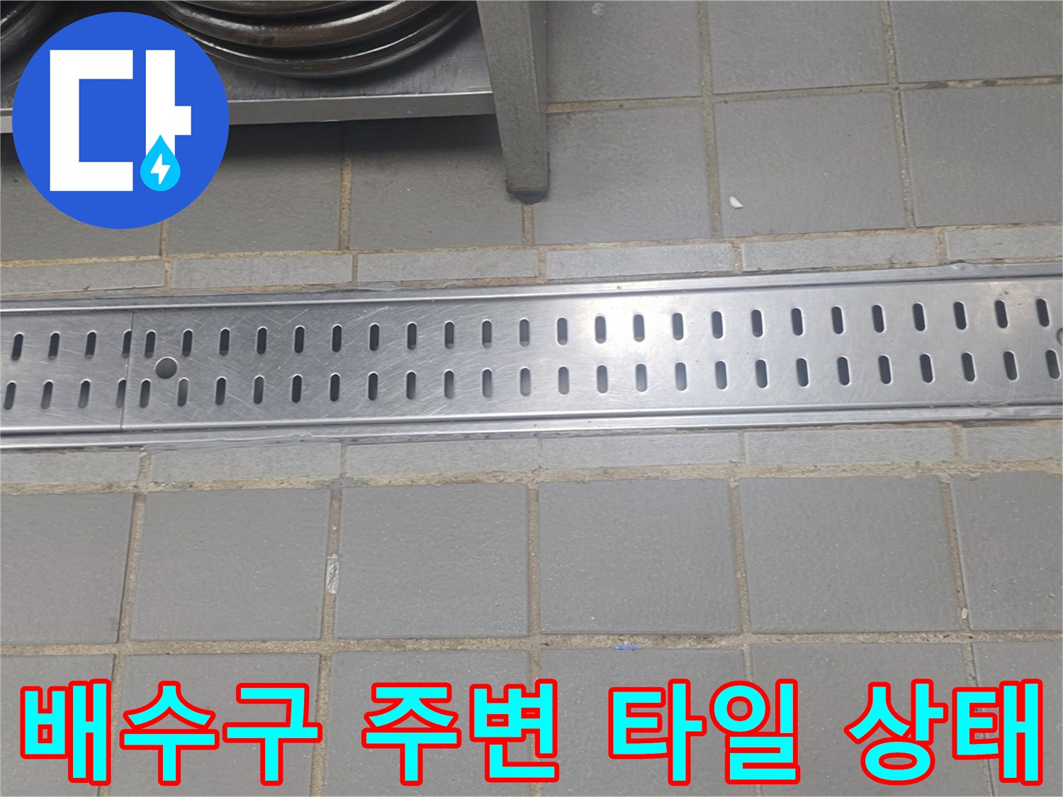 회색 타일과 금속 배수 트렌치가 맞닿은 지점의 근접 촬영