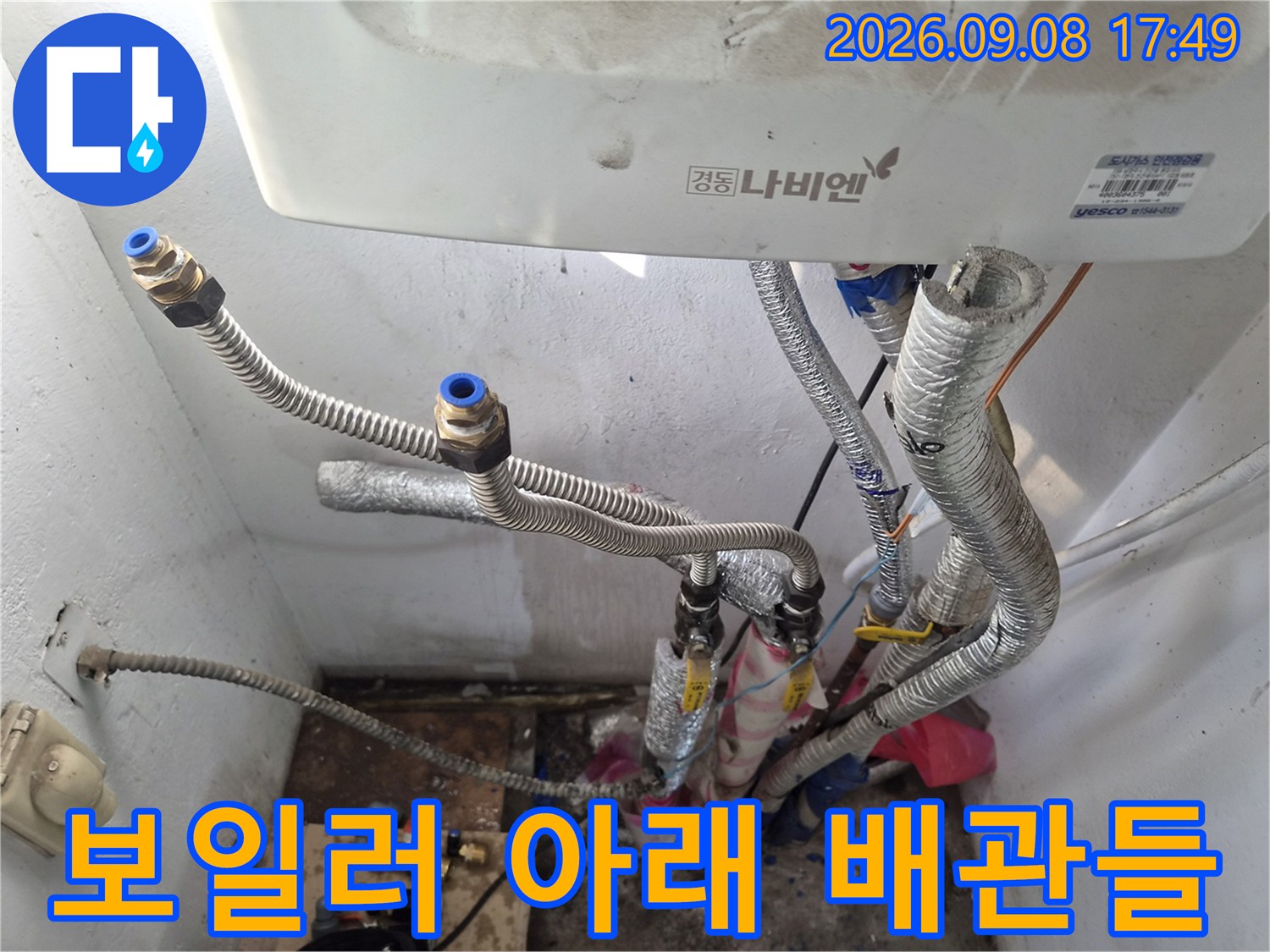 보일러 밑으로 연결된 은색 금속 소재의 배관 모습