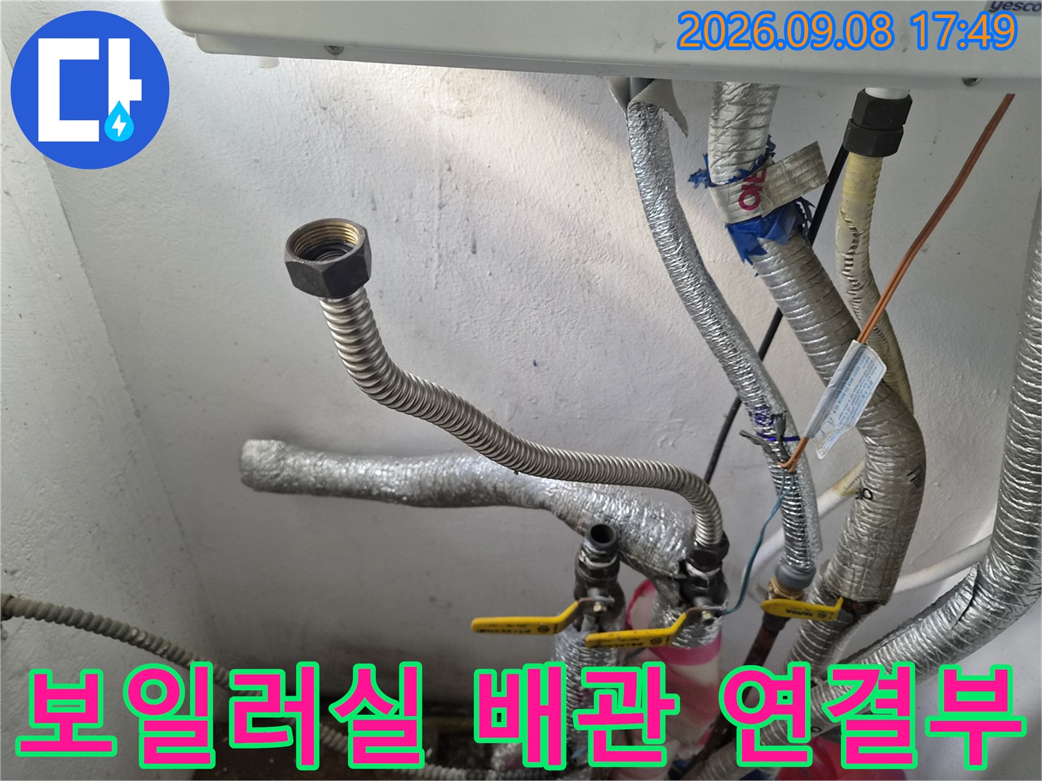 보일러 하단의 금속 배관과 밸브가 모여 있는 현장 모습입니다.