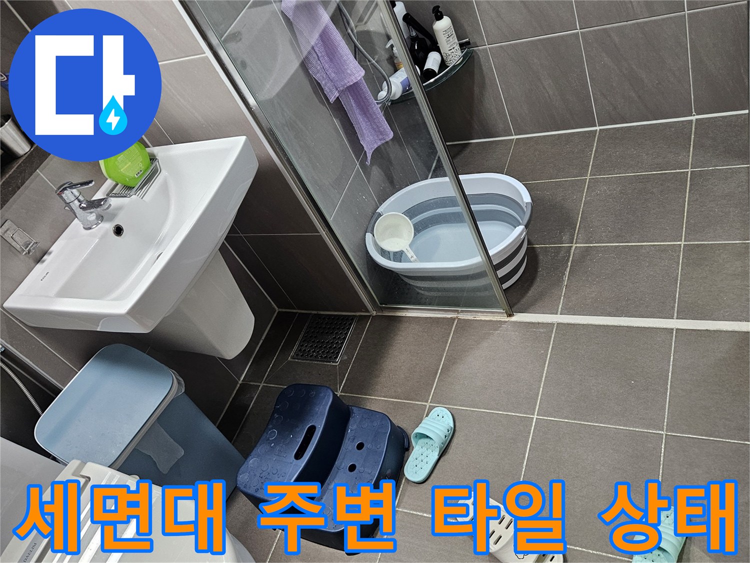 욕실 벽면의 회색 타일과 세면대 하단 부위 촬영