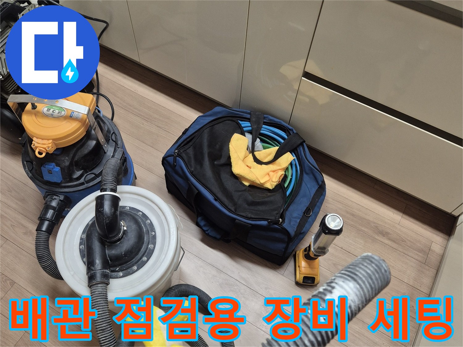 싱크대 아래 바닥에 배치된 압력 측정 게이지와 청소기 및 작업 도구들