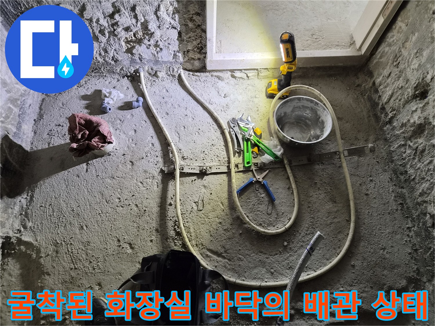 공사 중인 거친 바닥면과 노출된 흰색 배관 및 작업용 집게류
