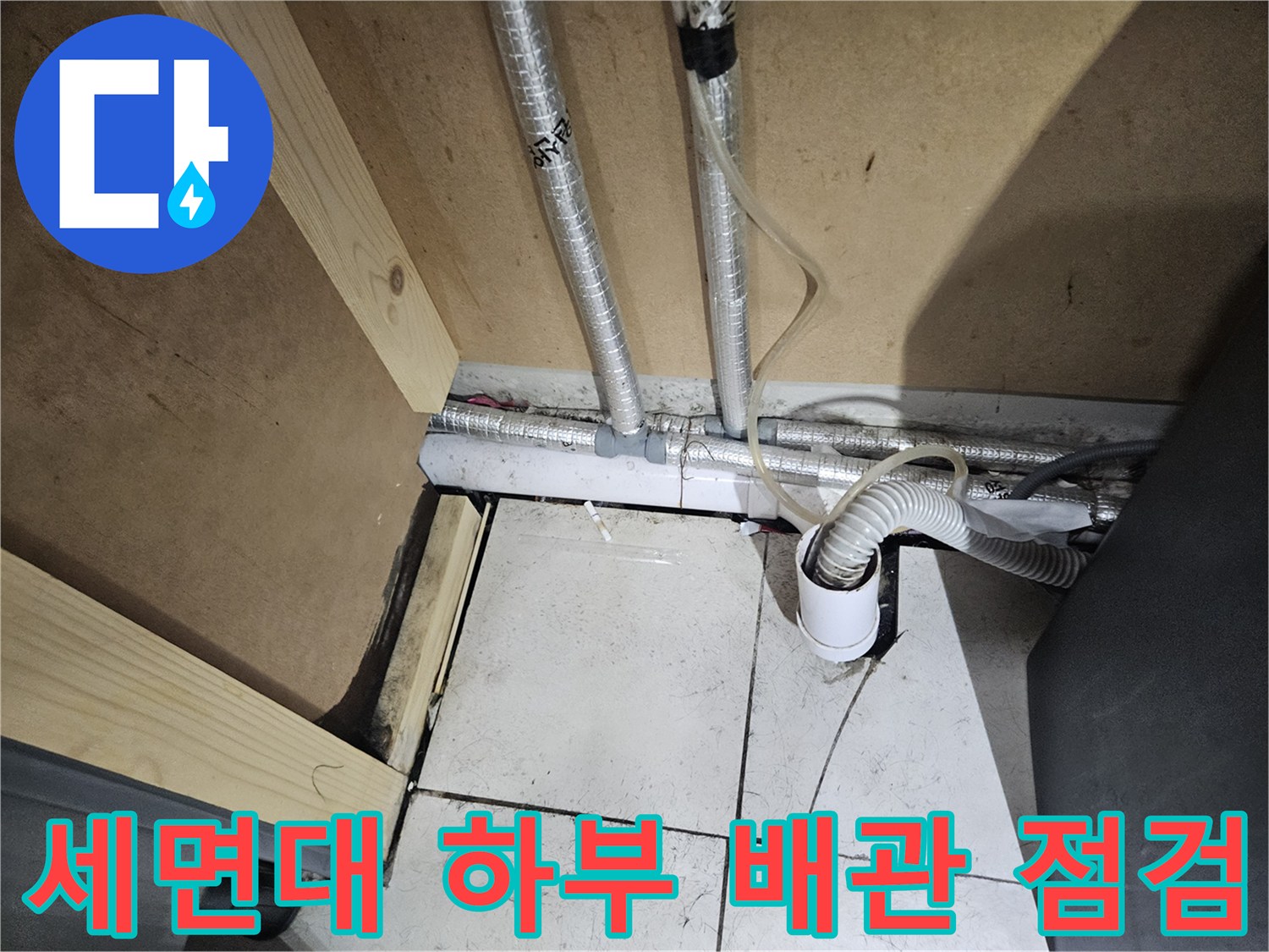 세면대 아래 복잡하게 얽힌 은색 배관들의 연결 상태