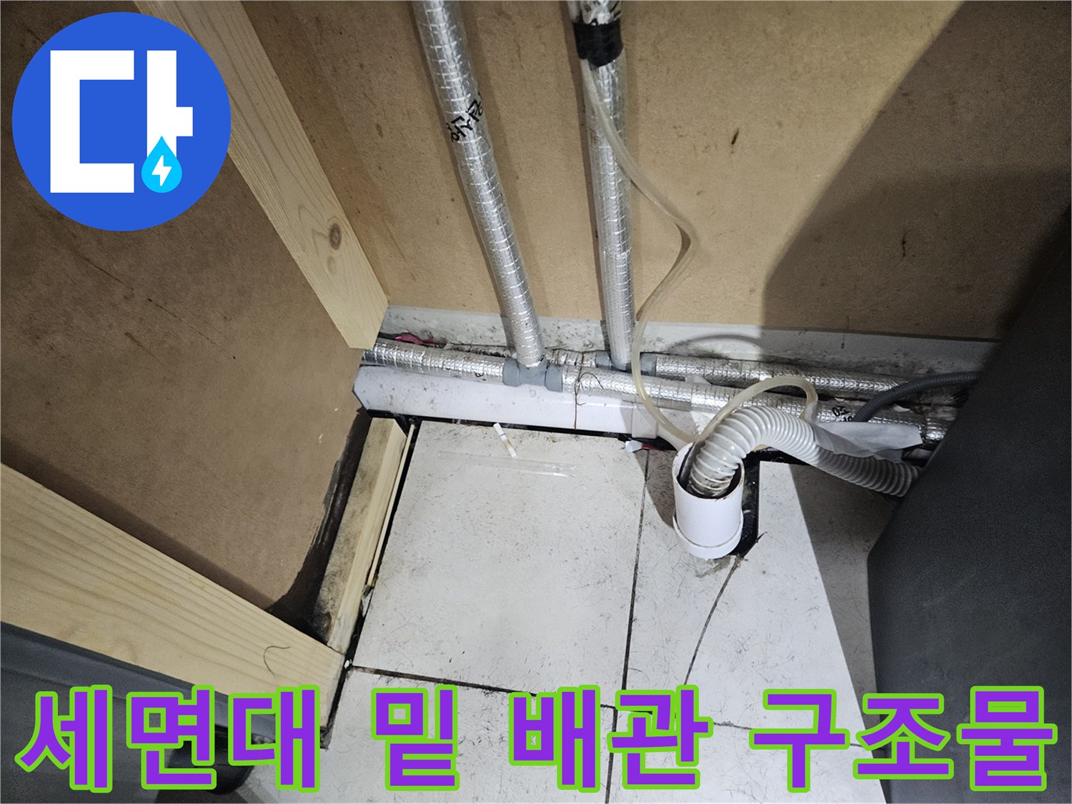 세면대 아래쪽의 은색 배관과 타일 벽면 연결 부위 상세