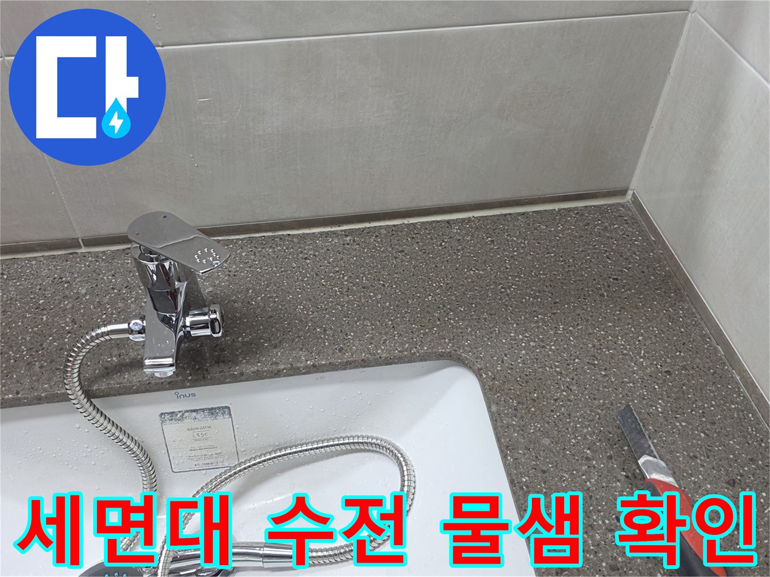 세면대 하단 수전과 연결된 은색 호스 및 벽면