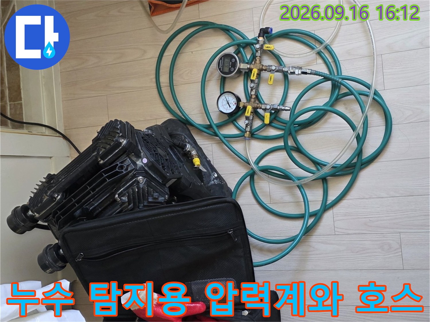 작업을 위해 바닥에 놓인 누수 탐지용 압력 게이지와 청색 연결 호스들