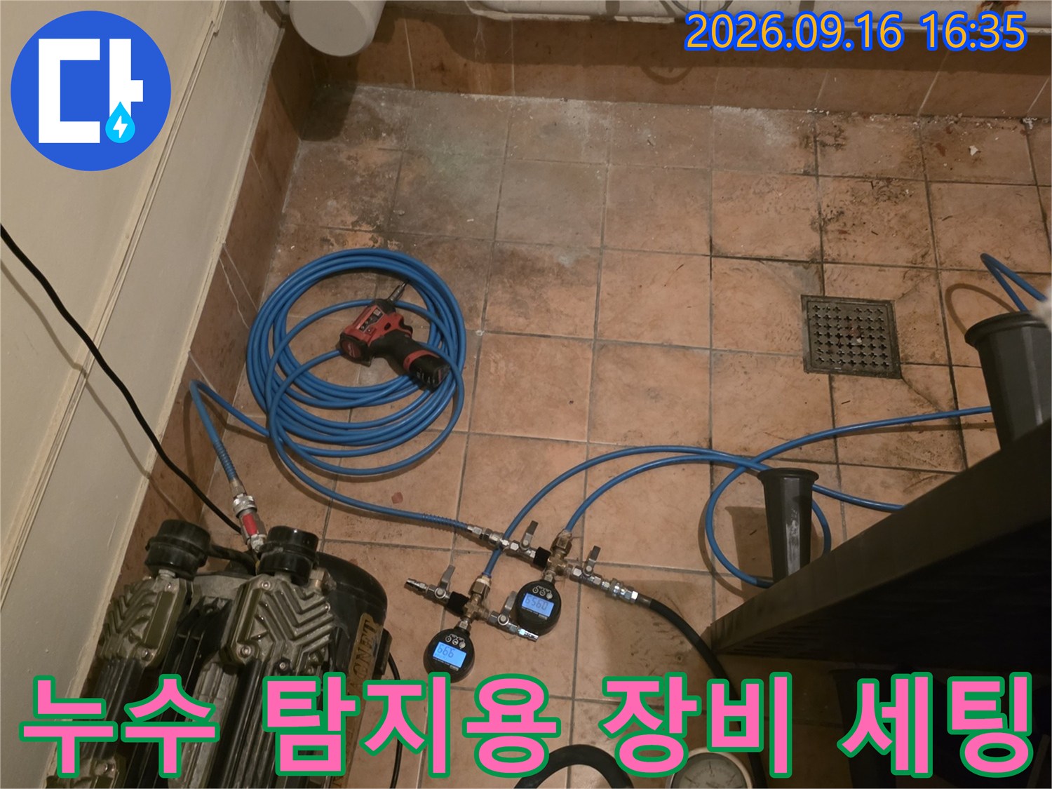 바닥 타일 위에 설치된 누수 검사용 압력 게이지와 콤프레셔