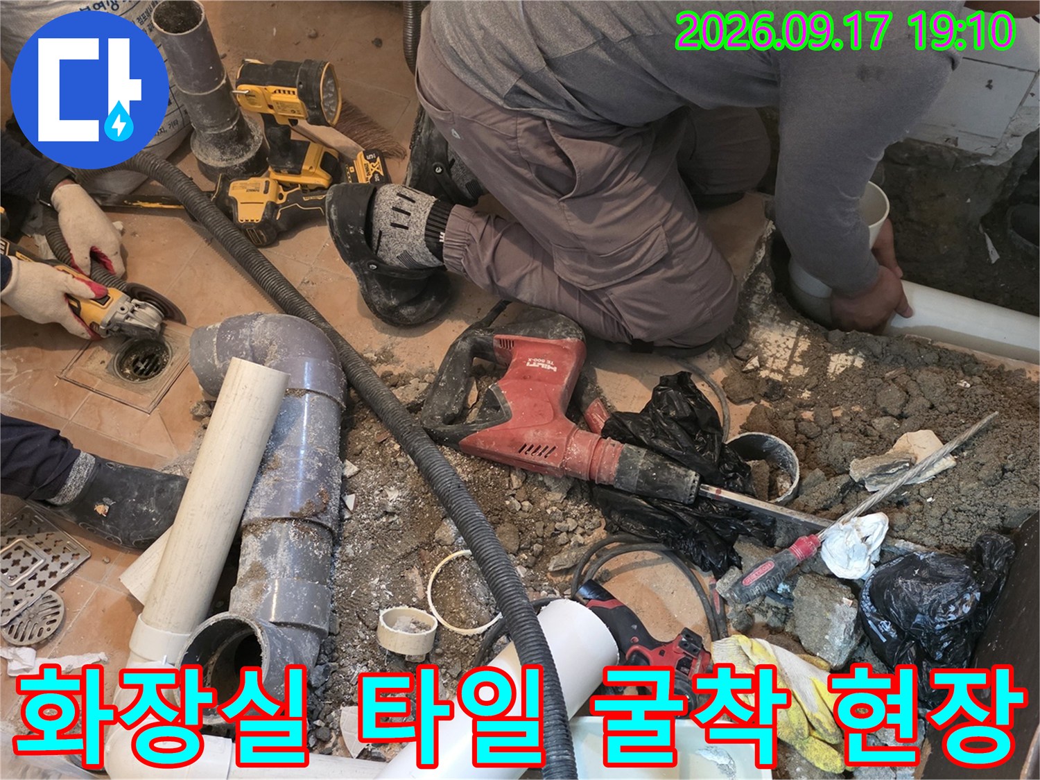 바닥을 깨고 드러난 배수관과 공사를 위해 사용 중인 전동 드릴