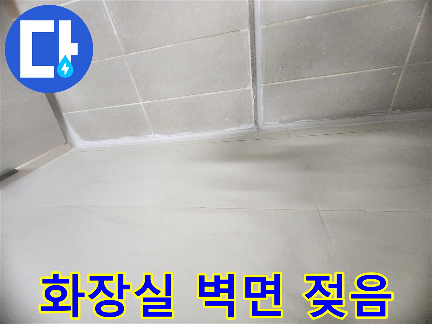 물기가 스며들어 어둡게 변한 화장실 타일 하단