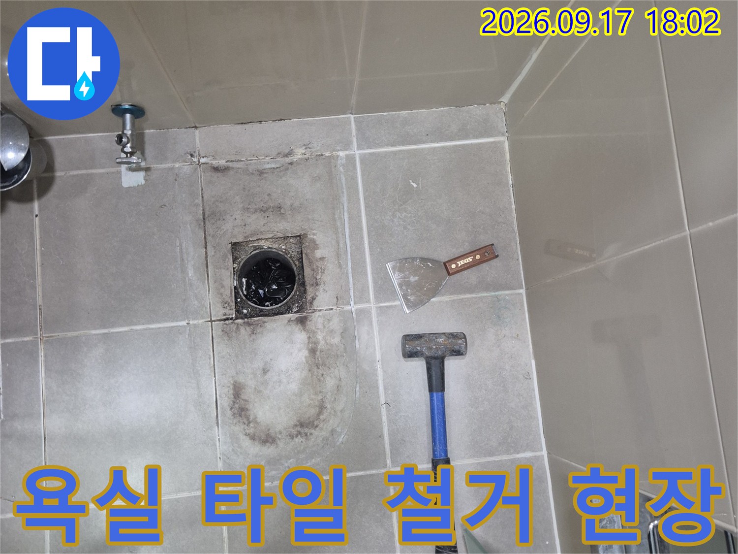 망치와 헤라를 사용하여 욕실 바닥 타일을 제거하는 작업 모습입니다.