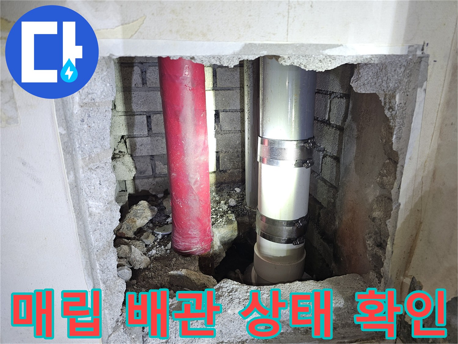 아파트 벽면 내부-노후된 붉은색 배관과 회색 배관의 연결 상태를 점검하는 모습